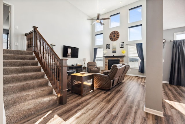 living room featuring a fireplace, stairway, a ceiling fan, wood finished floors, and baseboards