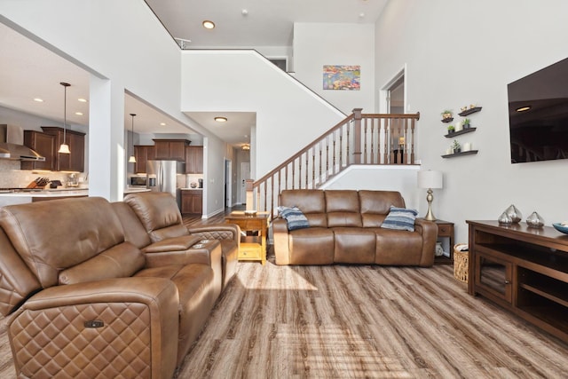 living room featuring light wood-style floors, recessed lighting, stairway, and a high ceiling