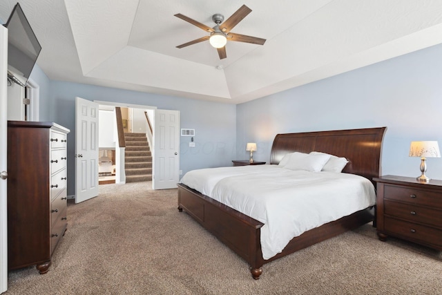 bedroom with a tray ceiling, carpet flooring, and ceiling fan