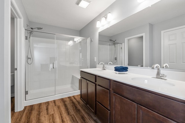 full bath featuring a stall shower, a sink, and wood finished floors