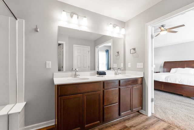 ensuite bathroom featuring double vanity, wood finished floors, a sink, and ensuite bathroom