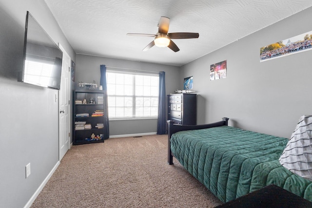 carpeted bedroom featuring ceiling fan, baseboards, and a textured ceiling