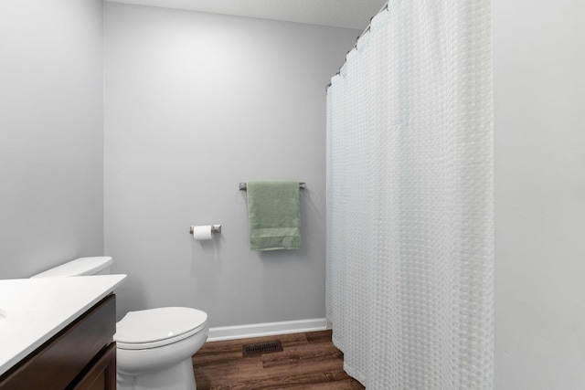 bathroom with toilet, wood finished floors, visible vents, vanity, and baseboards