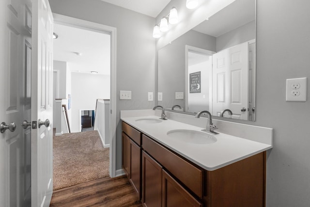 bathroom featuring double vanity, baseboards, a sink, and wood finished floors