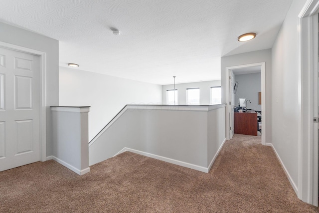 corridor featuring baseboards, carpet flooring, and an upstairs landing