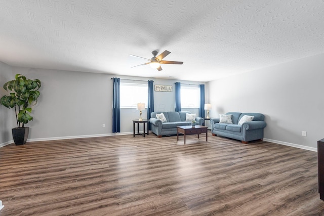 living area featuring dark wood-type flooring, ceiling fan, a textured ceiling, and baseboards