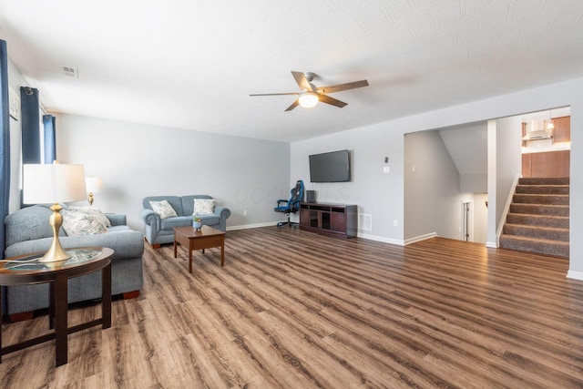 living area featuring ceiling fan, wood finished floors, visible vents, baseboards, and stairway