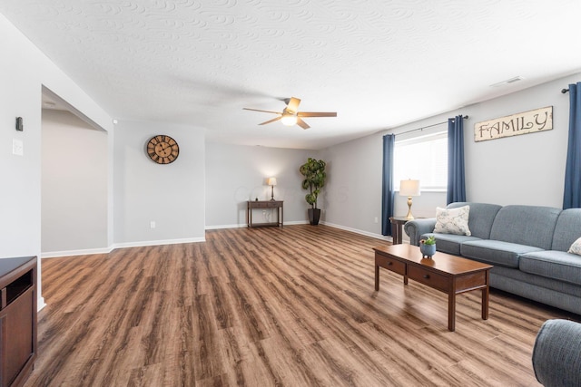 living area featuring ceiling fan, a textured ceiling, wood finished floors, and baseboards