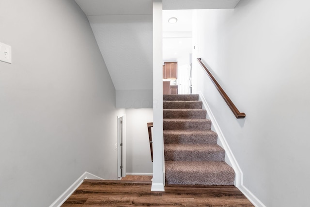 stairway with wood finished floors and baseboards