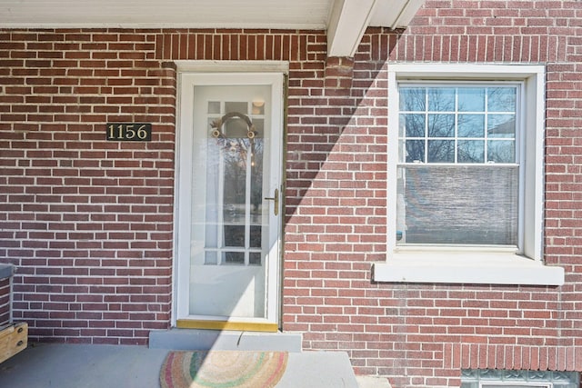 view of exterior entry featuring brick siding