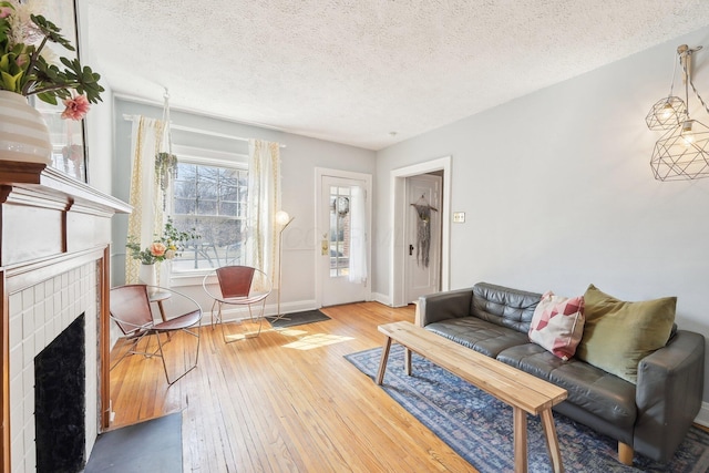 living room featuring hardwood / wood-style flooring, a fireplace with flush hearth, baseboards, and a textured ceiling