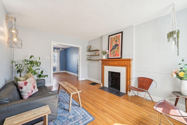 living room featuring a chandelier, a tile fireplace, baseboards, and wood finished floors