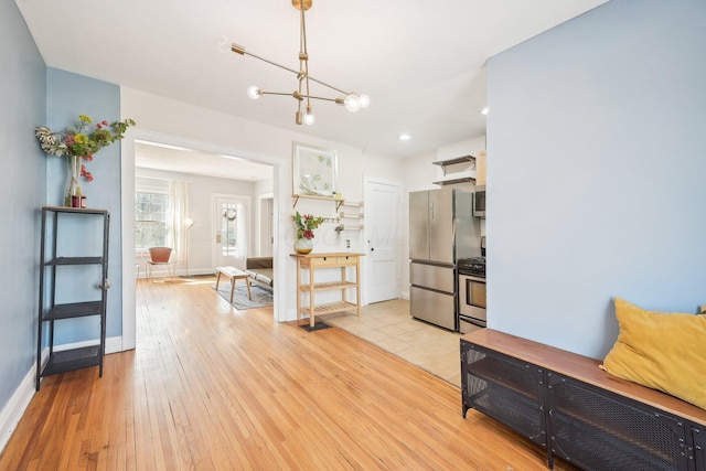 kitchen featuring baseboards, light wood finished floors, recessed lighting, stainless steel appliances, and a notable chandelier