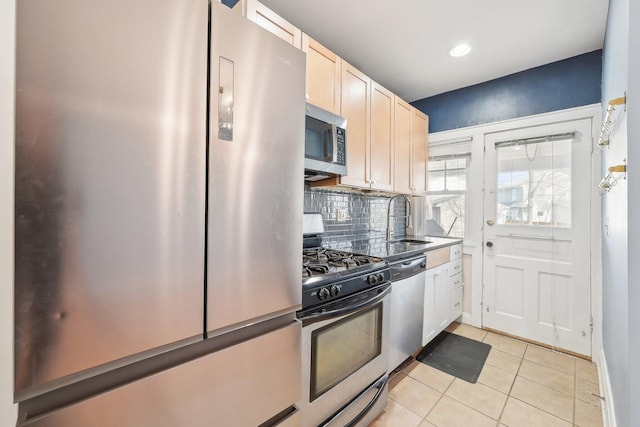 kitchen with light tile patterned floors, recessed lighting, a sink, appliances with stainless steel finishes, and backsplash