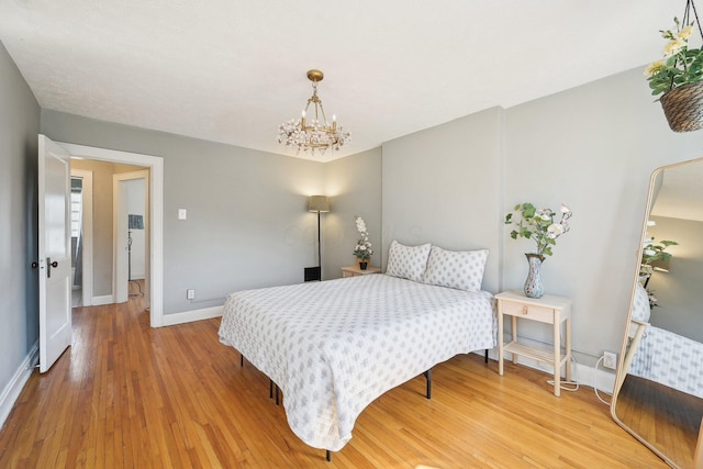 bedroom with baseboards, a notable chandelier, and light wood finished floors