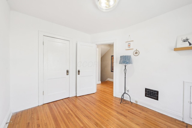 unfurnished bedroom with visible vents, light wood-type flooring, and baseboards