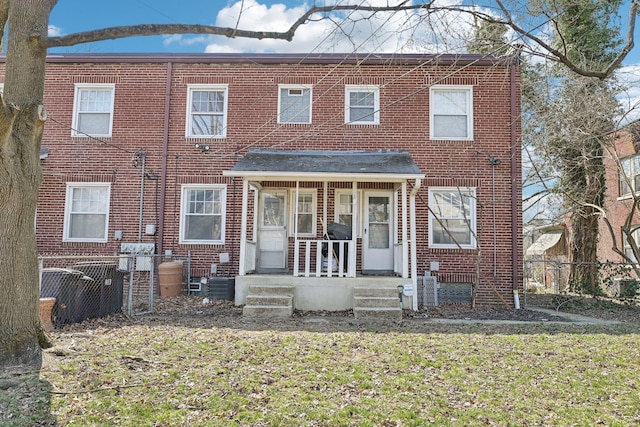 exterior space with brick siding, a porch, and fence