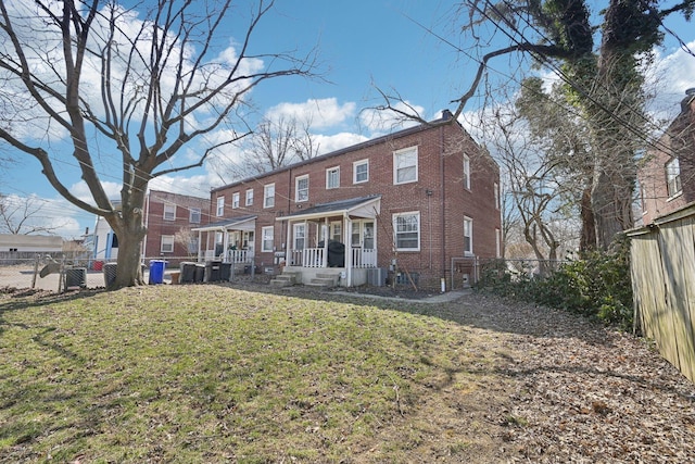 back of property featuring a lawn, a porch, a fenced backyard, and brick siding