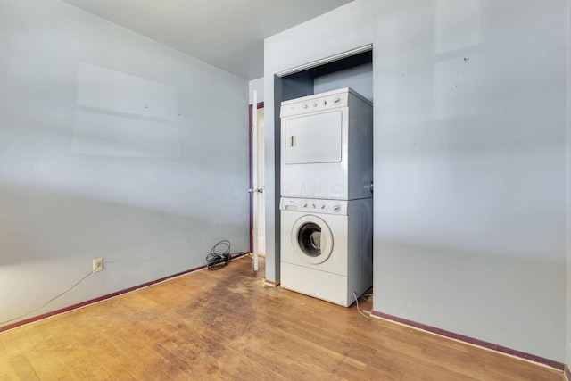 washroom with stacked washer / drying machine and hardwood / wood-style floors