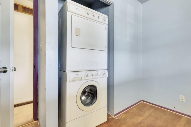 laundry area with stacked washer and dryer and wood-type flooring