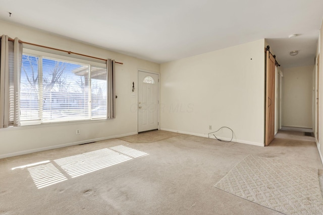 empty room with a barn door and light colored carpet