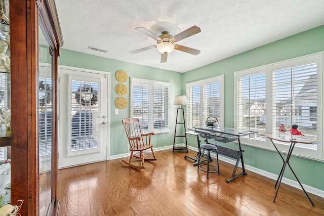 home office featuring ceiling fan, light hardwood / wood-style floors, and a textured ceiling