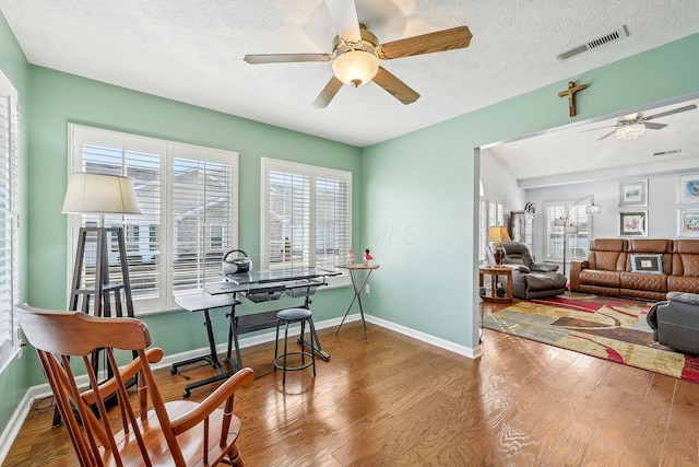 interior space featuring ceiling fan, wood-type flooring, and a textured ceiling