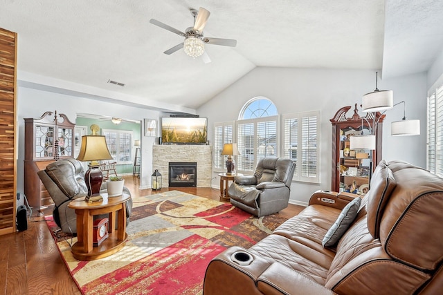 living room with ceiling fan, a fireplace, a textured ceiling, dark hardwood / wood-style flooring, and vaulted ceiling