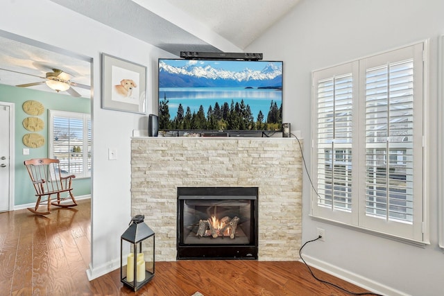 details with ceiling fan, a stone fireplace, hardwood / wood-style floors, and a textured ceiling