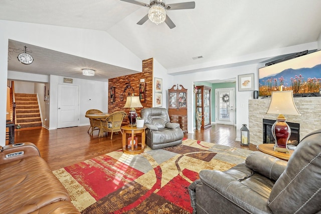 living room featuring a stone fireplace, wood-type flooring, ceiling fan, and vaulted ceiling