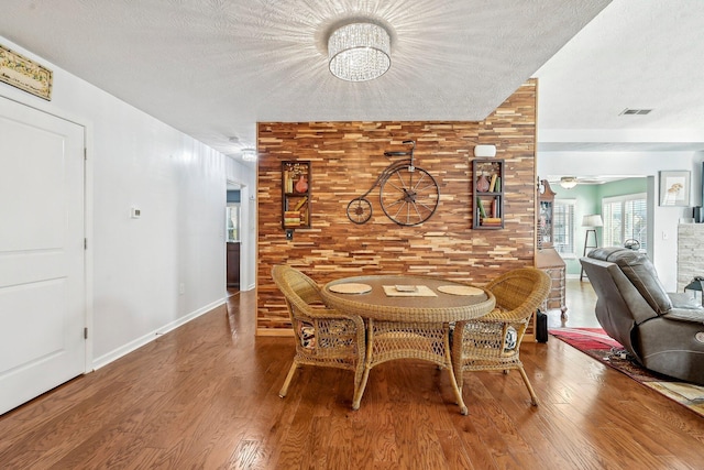 dining room featuring wood-type flooring, a chandelier, and a textured ceiling