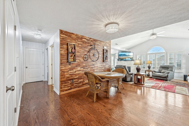 dining room featuring ceiling fan, wood-type flooring, a textured ceiling, and vaulted ceiling