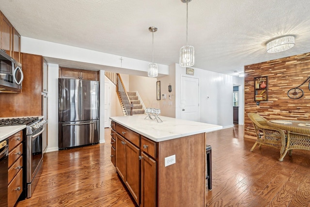 kitchen featuring hanging light fixtures, stainless steel appliances, dark hardwood / wood-style floors, and a kitchen island