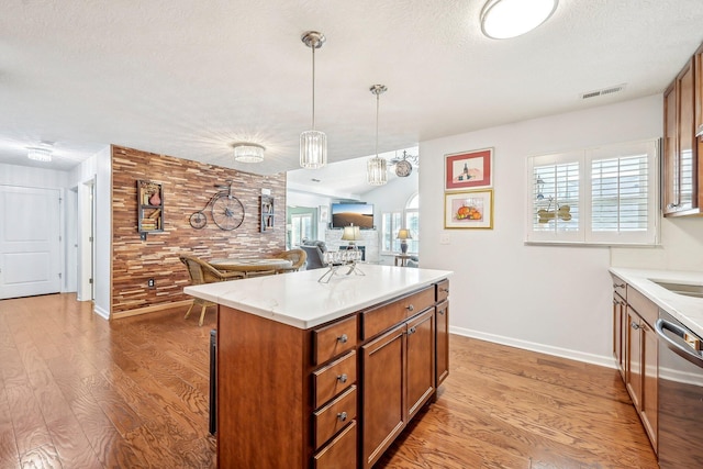 kitchen featuring plenty of natural light, decorative light fixtures, dishwasher, and light wood-type flooring