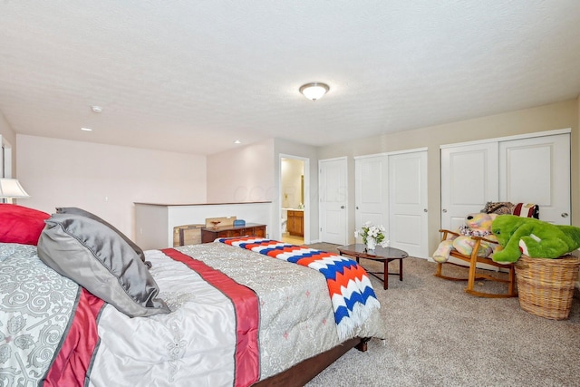 carpeted bedroom featuring connected bathroom, a textured ceiling, and multiple closets