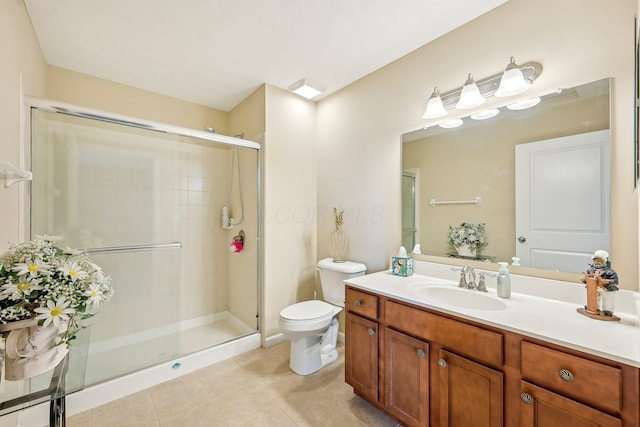 bathroom featuring tile patterned floors, vanity, toilet, and a shower with door