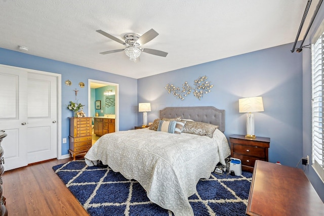 bedroom with hardwood / wood-style flooring, ceiling fan, and ensuite bath