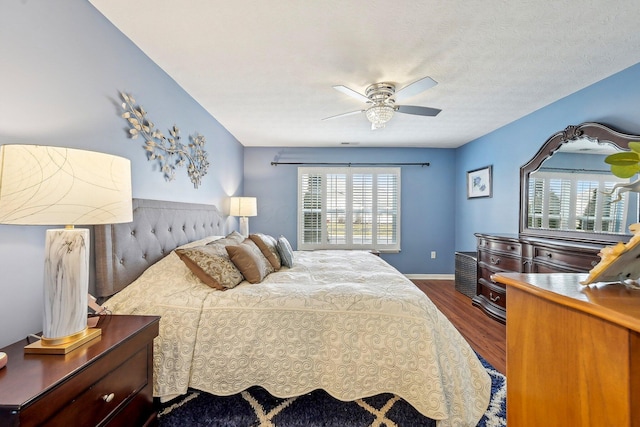 bedroom featuring dark wood-type flooring, a textured ceiling, and ceiling fan