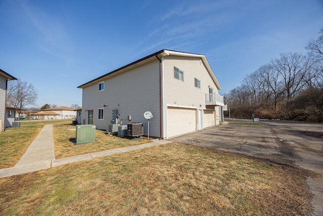 view of home's exterior with cooling unit, a garage, and a yard