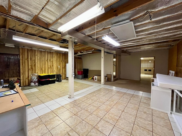 basement with wooden walls and light tile patterned floors