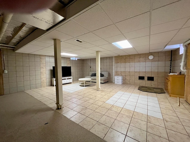 basement featuring a paneled ceiling and light tile patterned floors