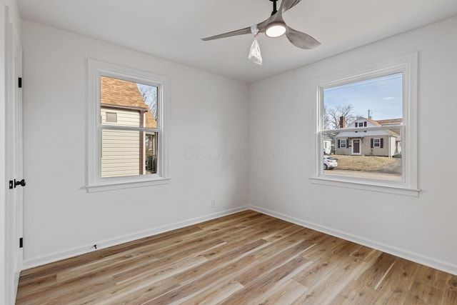 empty room with ceiling fan, a wealth of natural light, and light wood-type flooring