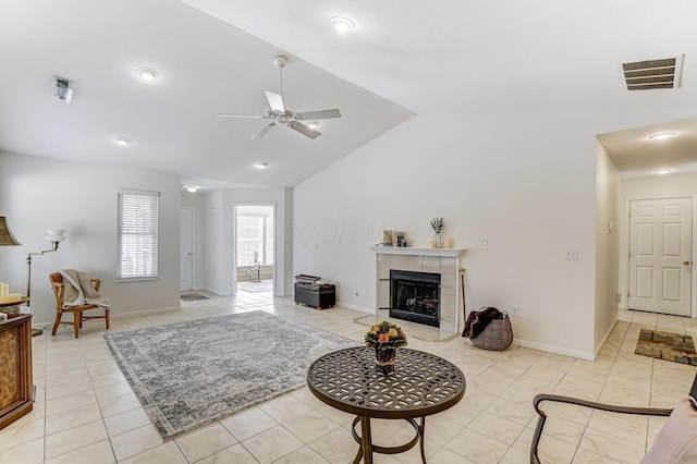 tiled living room with lofted ceiling, a tile fireplace, and ceiling fan