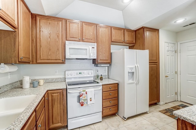 kitchen with light tile patterned flooring, white appliances, vaulted ceiling, and sink