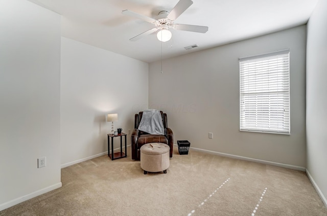 living area with light colored carpet and ceiling fan