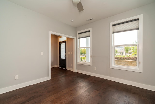 spare room with ceiling fan, dark wood-type flooring, and a healthy amount of sunlight