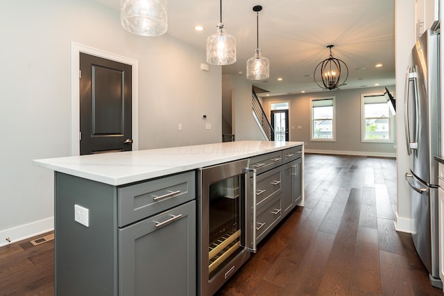 kitchen with pendant lighting, gray cabinets, stainless steel refrigerator, wine cooler, and a kitchen island