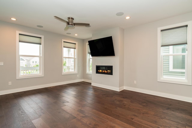 unfurnished living room featuring dark wood-type flooring and ceiling fan