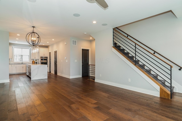 unfurnished living room with dark hardwood / wood-style floors, sink, and an inviting chandelier