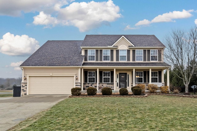 colonial-style house featuring a garage, covered porch, and a front yard